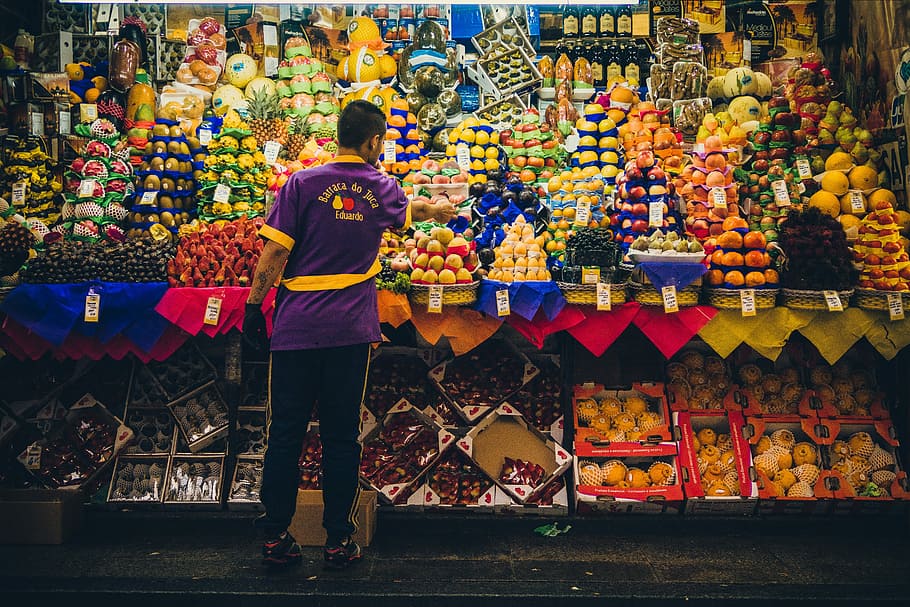man standing in front of produce stand, man standing in front of fruit stand