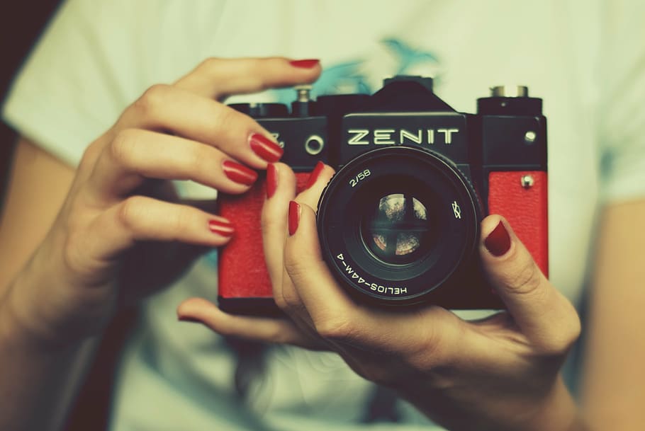 person holding red and black Zenit SLR camera, zenith, lens, retro camera