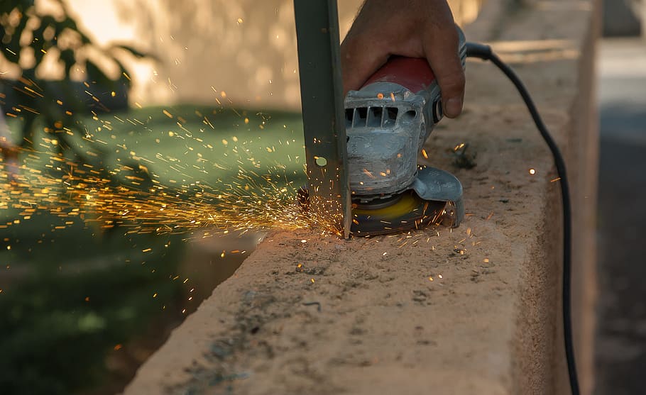 person cutting gray metal using corded angle grinder, tool HD wallpaper