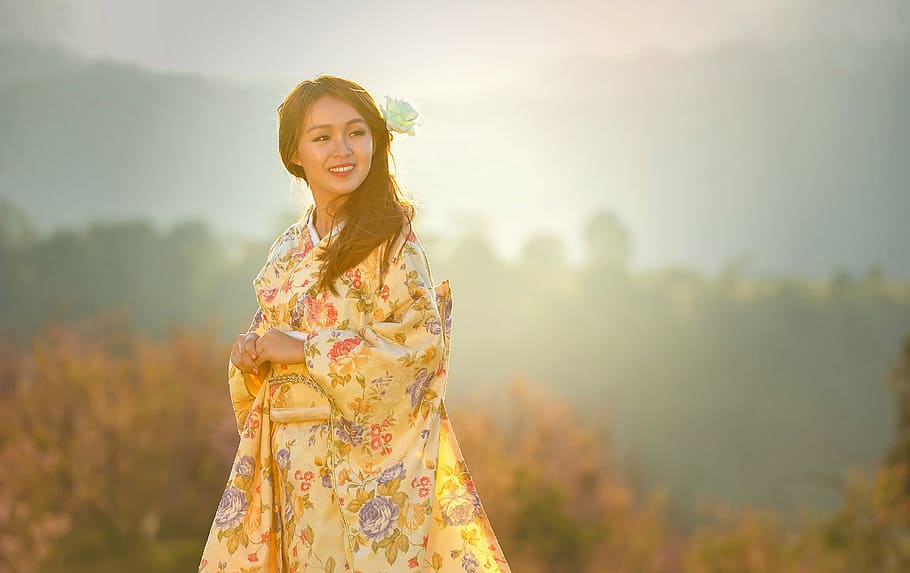 selective focus photography of woman wearing yellow and green floral long-sleeved traditional dress