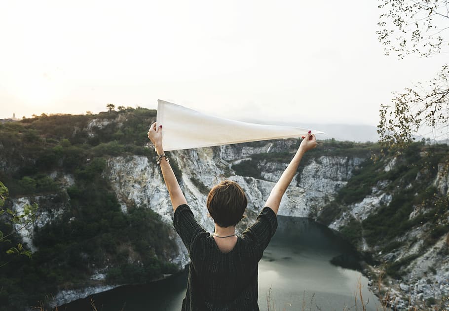 woman raising white flaglet in front of body of water, female, HD wallpaper