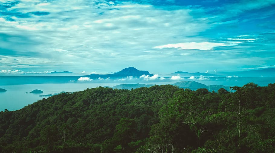 aerial photography of mountains near body of water, green leaf trees under blue sky during daytime HD wallpaper