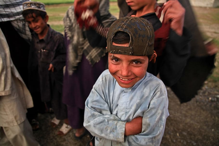 boy wearing blue long-sleeved top, afghani, child, laughing, poor