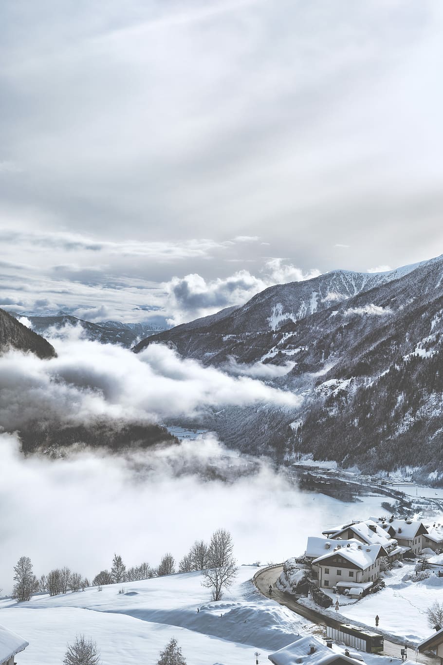 snow-covered village near mountains under white clouds during daytime, aerial photography of house near mountain HD wallpaper