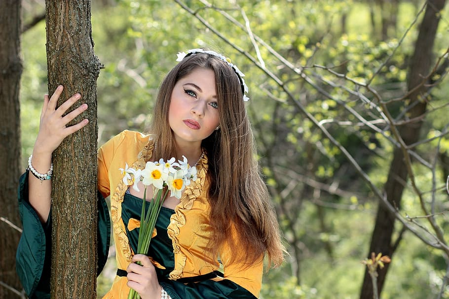 woman holding white petaled flowers standing beside brown tree trunk at daytime, HD wallpaper