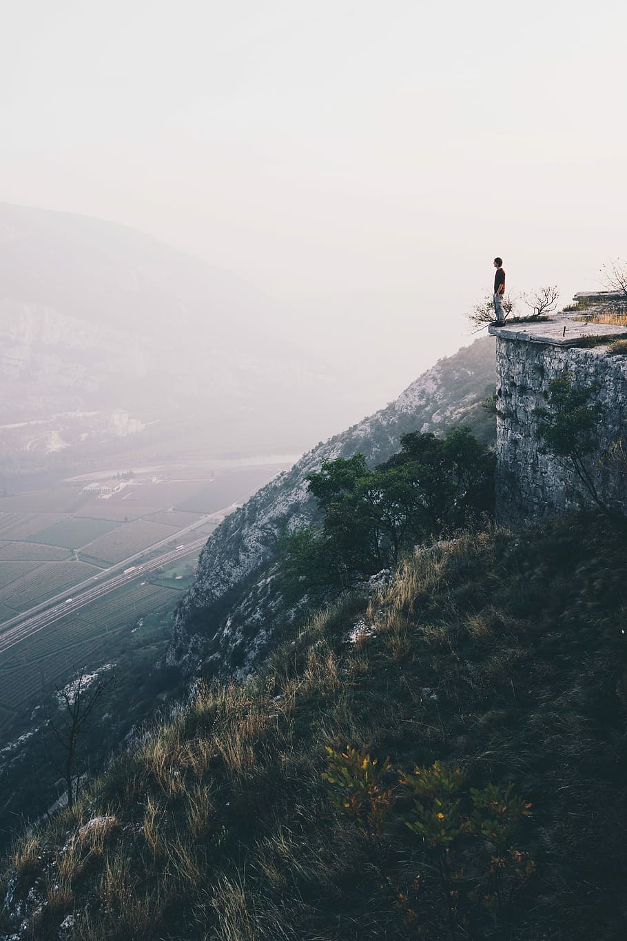 Hunter, person standing on cliff with overlooking view of green fields at daytime HD wallpaper