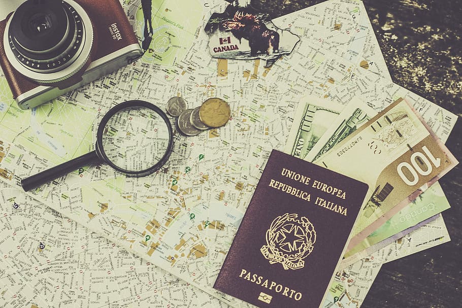 coin beside magnifying glass, brown passport book placed near magnifying glass