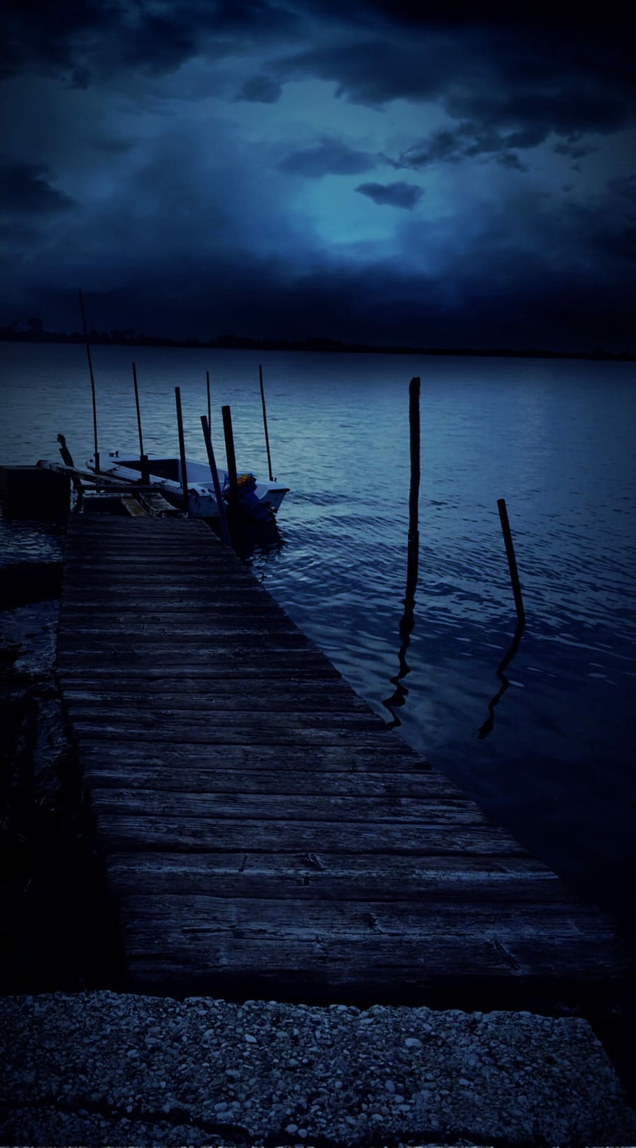 brown wooden dock with white motor boat on water at night time