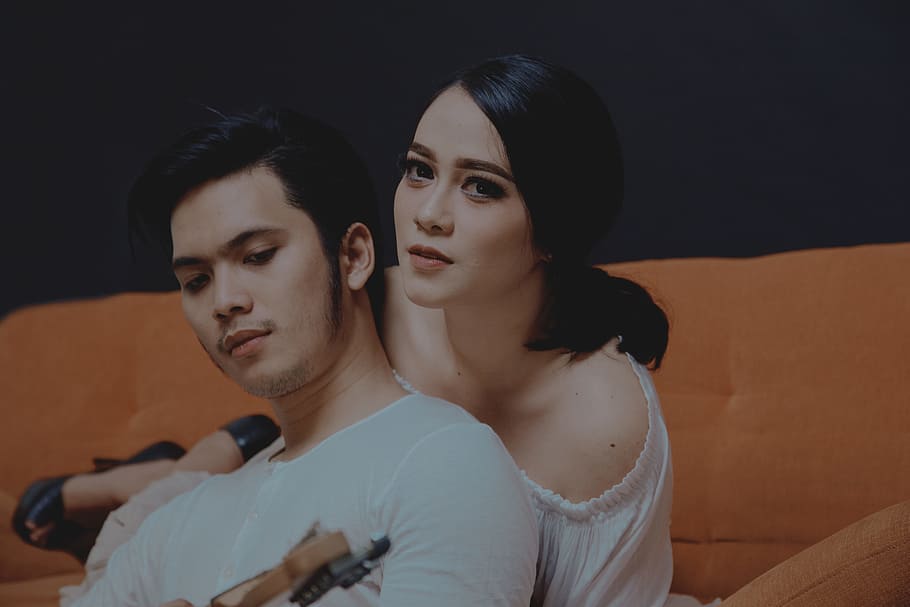 woman laying on orange couch, man and woman posing for photo HD wallpaper