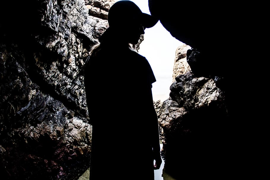 silhouette photography of person inside a cave during daytime HD wallpaper