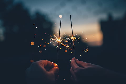 person holding fire cracker shallow focus photography, two persons holding firework sticks HD wallpaper