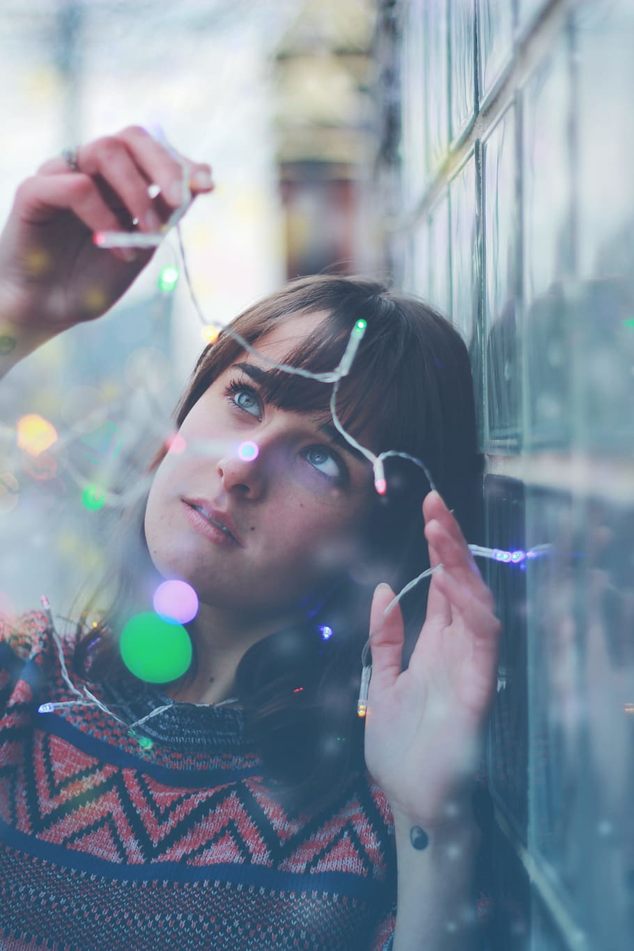 woman holding string lights, woman wearing orange and black crew-neck shirt holding string lights selective focus photography HD wallpaper