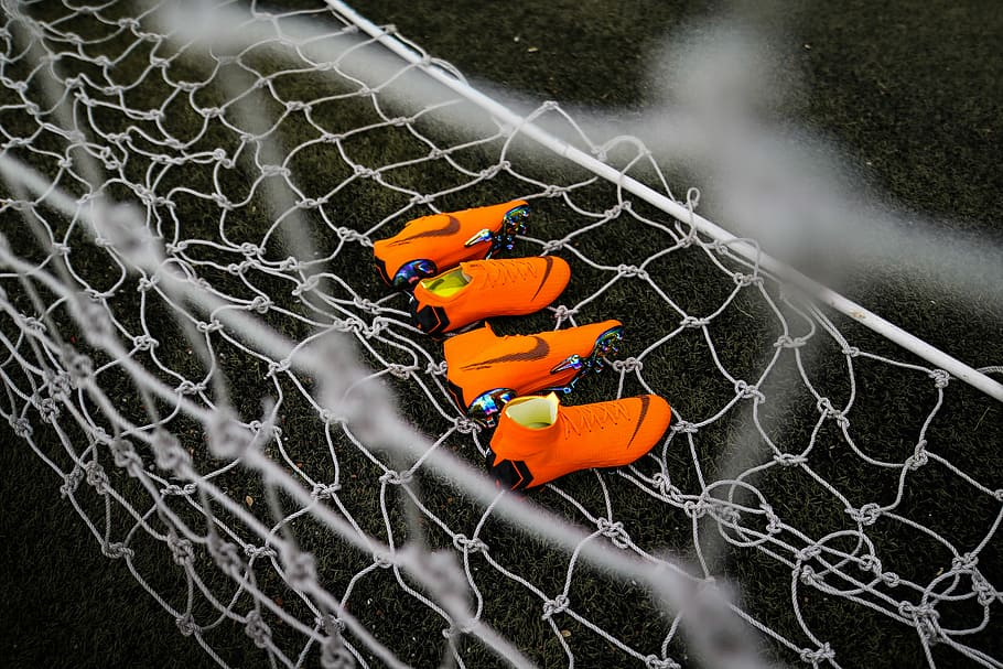 two pairs of orange Nike cleats on goalie, two pairs of orange Nike cleats on white soccer net, HD wallpaper