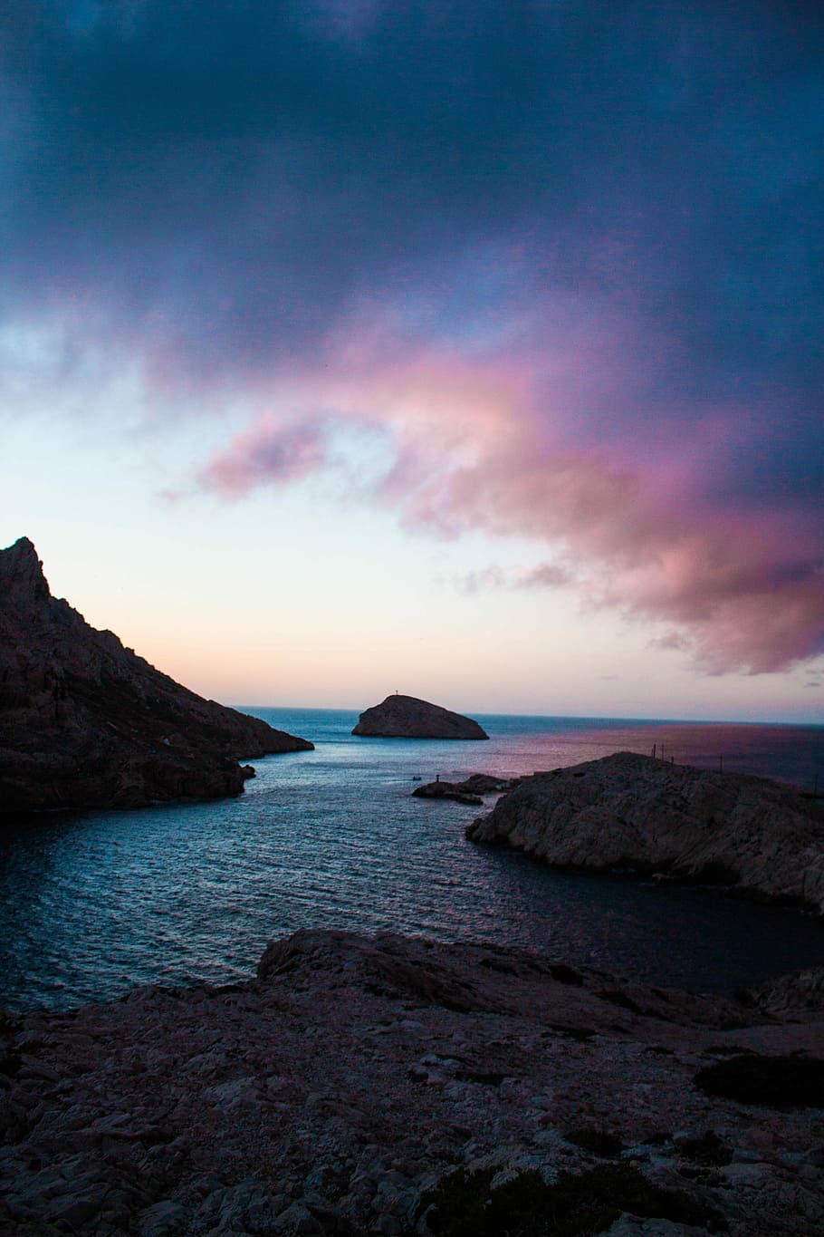 photo of body of water surrounded by rocks, cliff near body of water at cloudy sky during daytime HD wallpaper