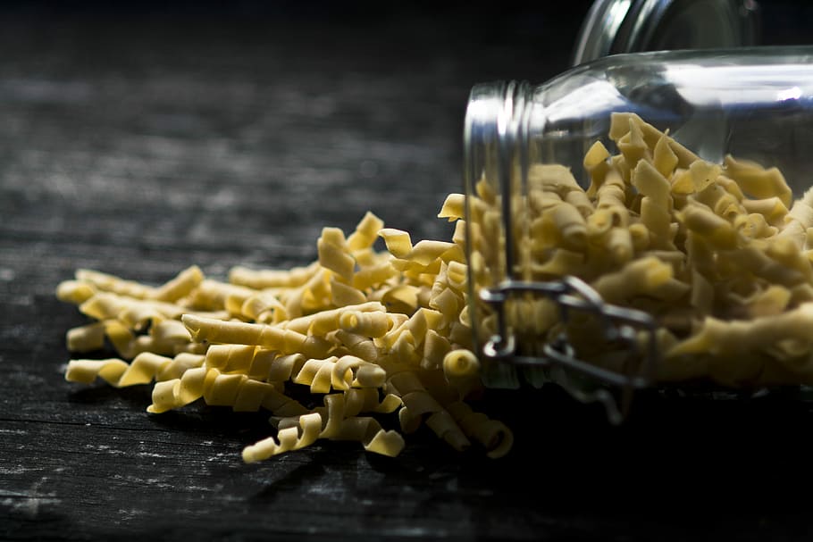 close up photo of yellow spiral pasta spilled jar, spiral pasta on black surface, HD wallpaper