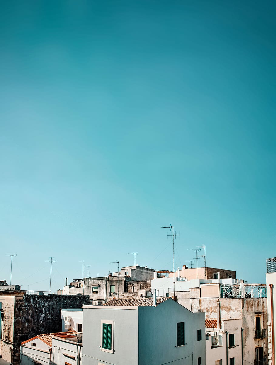 high rise buildings under teal sky during daytime, gray concrete building beside white concrete building HD wallpaper