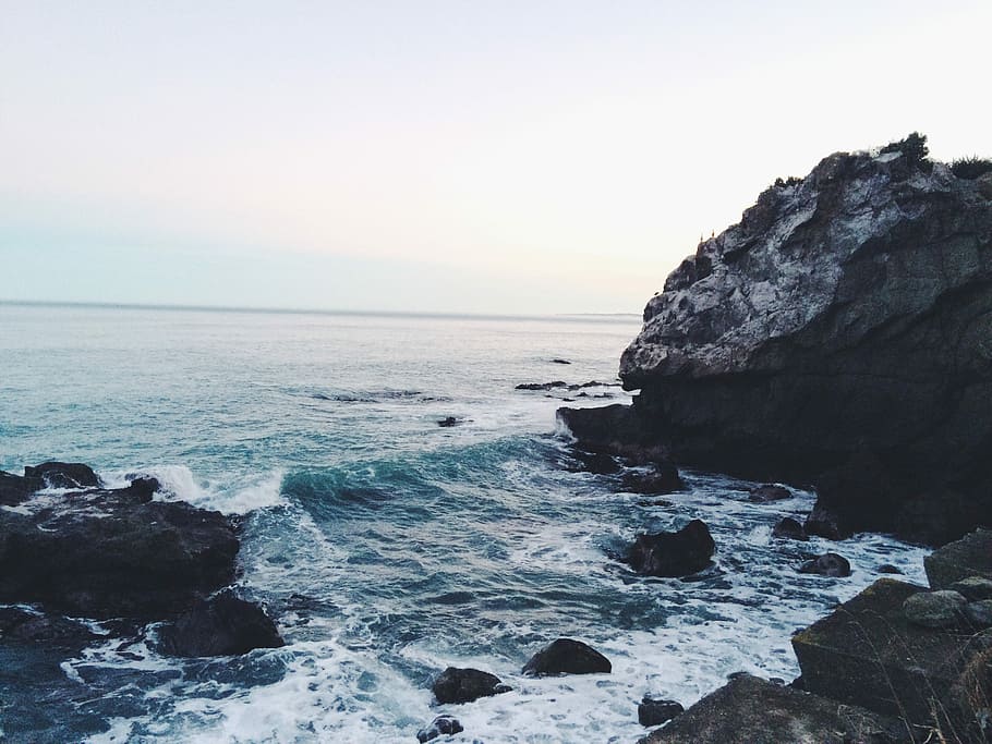 ocean waves near rocks during daytime, ocean waves hugging black rocky shore HD wallpaper
