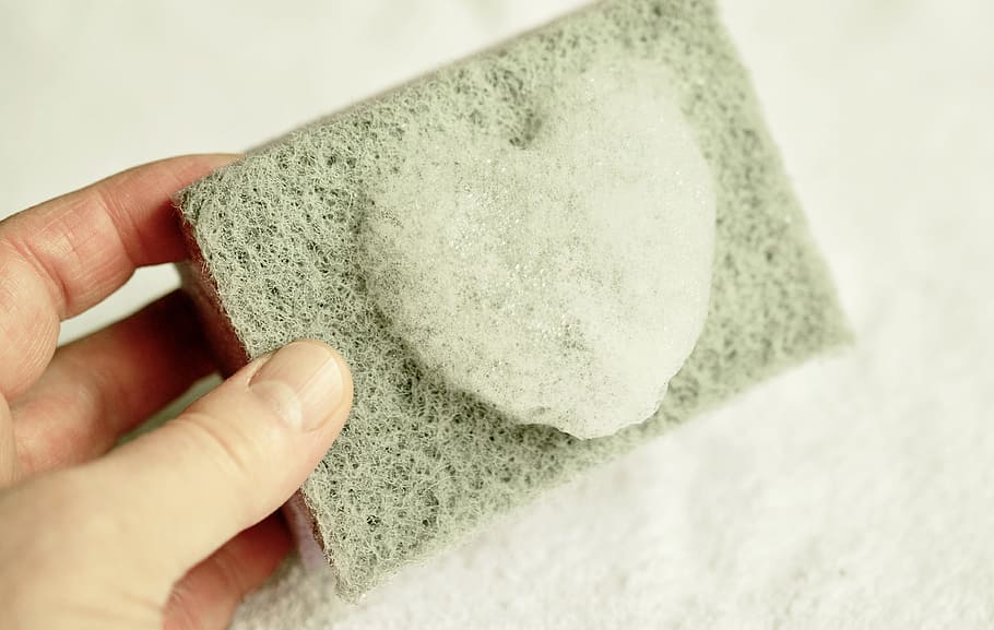 person holding gray heart stone mold, sponge, cleaning sponge