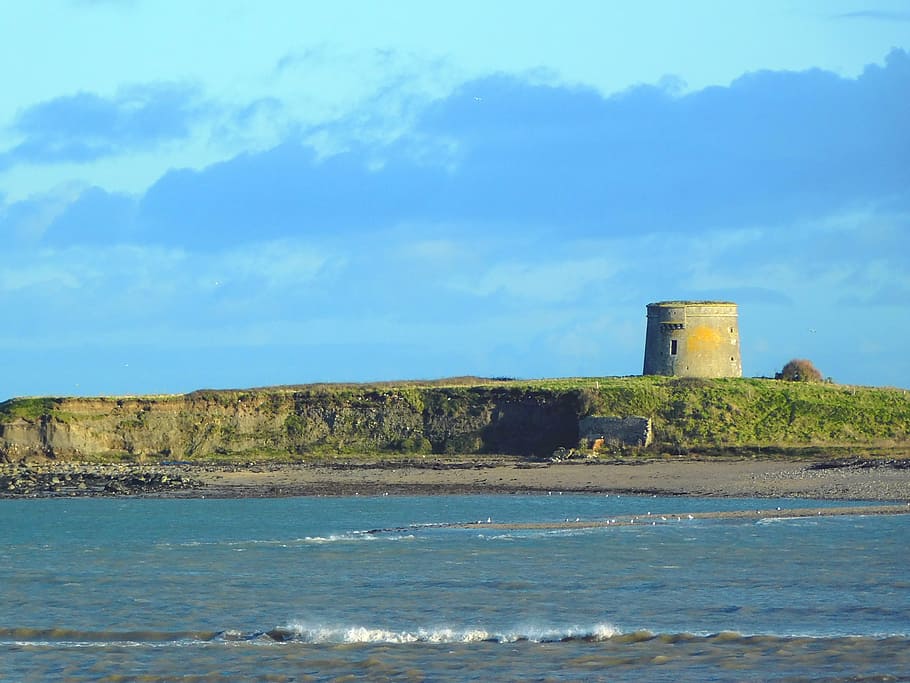 gray concrete tower by cliff near shore at daytime, martello tower