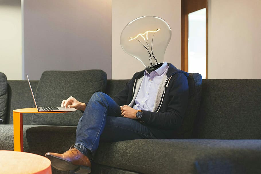 bulb-headed man sitting on sofa using laptop, lightbulb, workplace