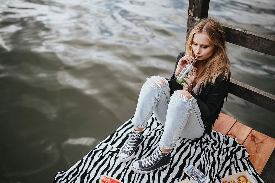 Blonde woman having a healthy snack at the wooden pier, female