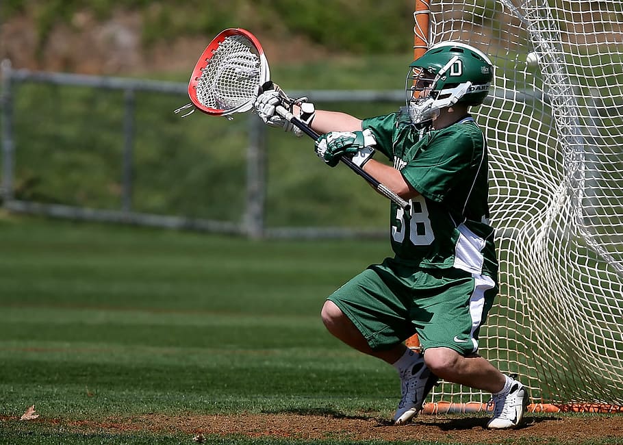 player in green jersey and shorts holding lacrosse stick, goalie