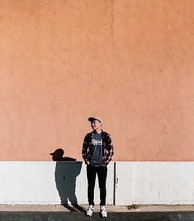 man standing in front of brown wall, man standing near orange and white wall during daytime HD wallpaper