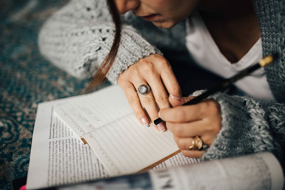 Woman in a grey sweater taking notes in an organizer, notebook HD wallpaper