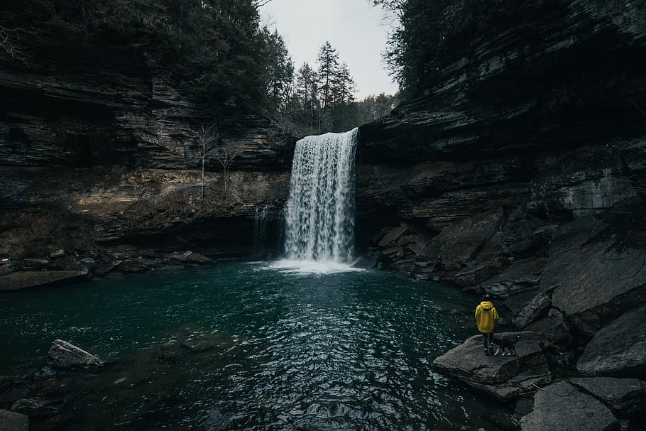 person in front of waterfalls, man standing on rock near waterfalls during daytime HD wallpaper