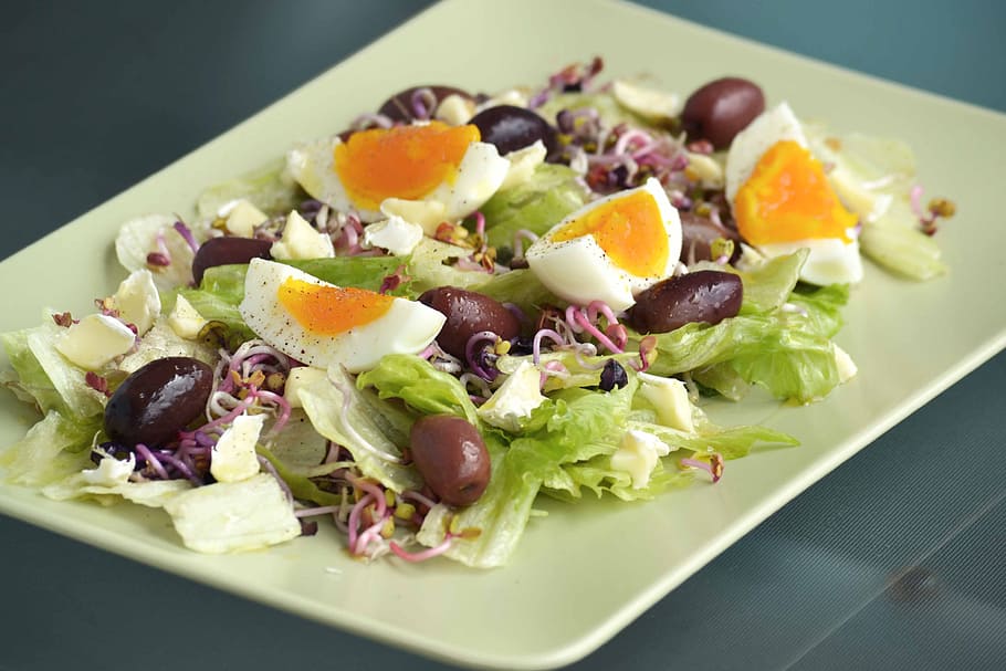 rectangular white plate with vegetable salad topped with sliced hard boiled egg