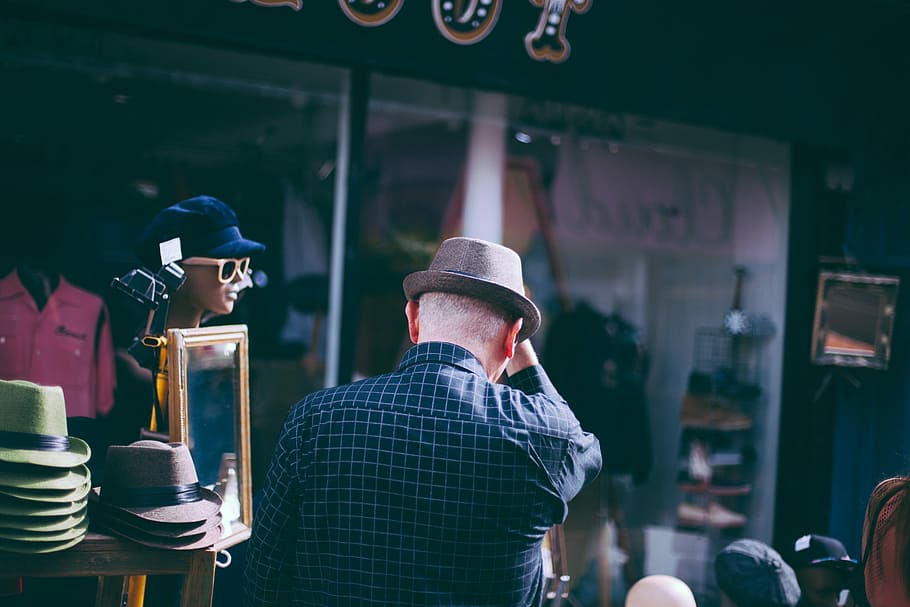 man holding his brown fedora hat facing backwards, man wearing brown hat near mirror HD wallpaper