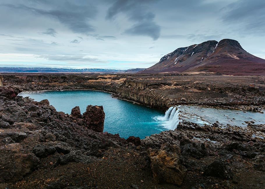 body of water surrounded by brown rocks at daytime, spring HD wallpaper