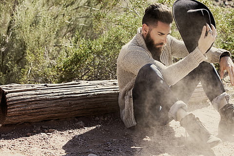 man holding hat sitting near wood trunk during daytime, men, outdoors HD wallpaper