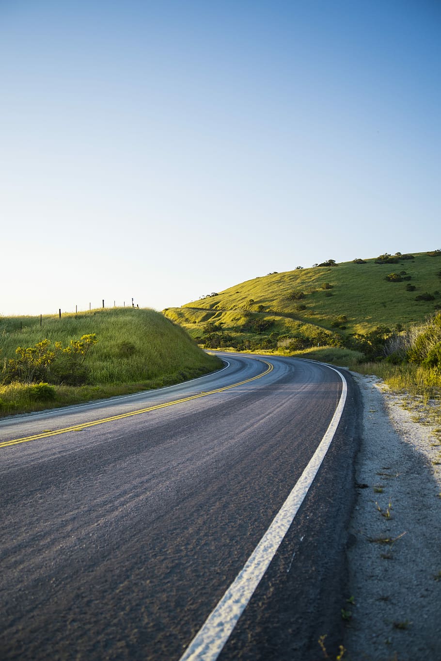 photo of black concrete road, concrete road between green grass at daytime HD wallpaper