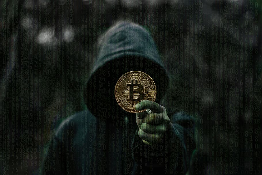 person showing round gold-colored Bitcoin coin, dark, blockchain