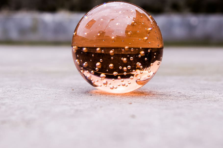 selective focus photography of amber glass ball, crystalball