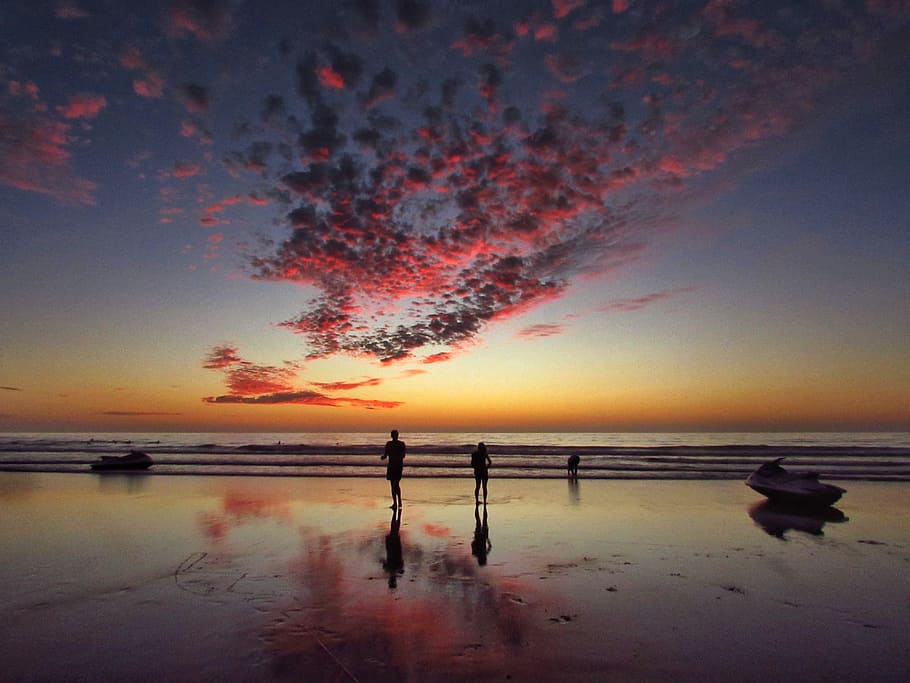 two person standing on shore, reflection photography of people at beach during golden hour HD wallpaper