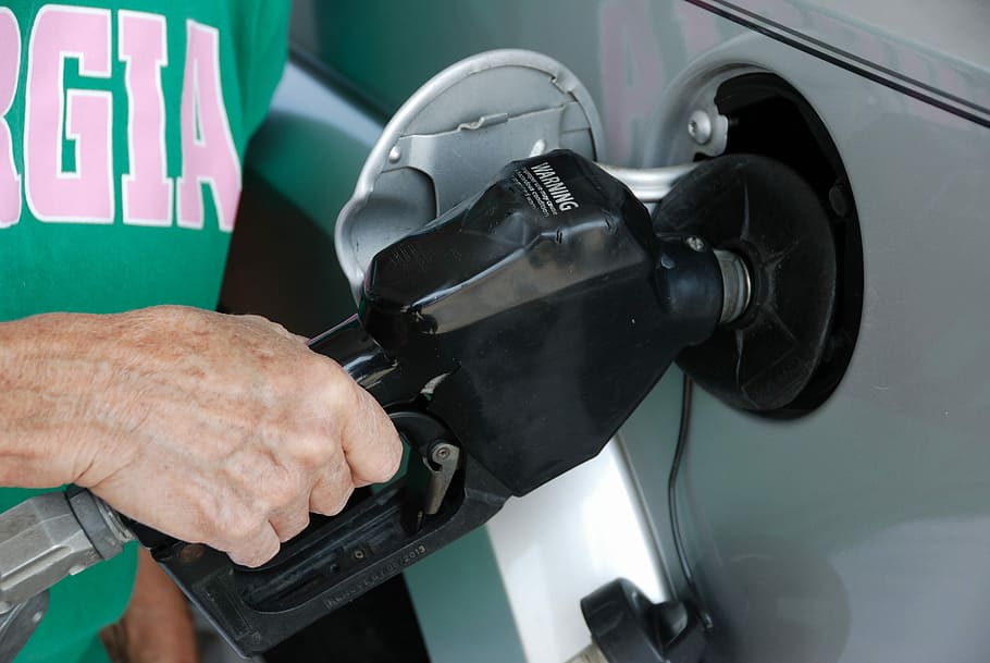 person holding black gas nozzle, Pumping Gas, Fuel, Pump, Industry