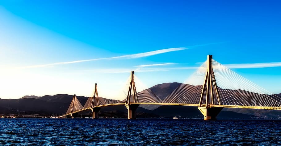 brown concrete bride across the sea under blue sky during daytime HD wallpaper