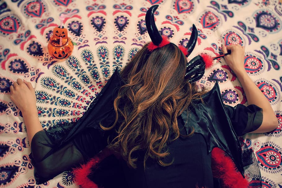 person wearing black dress and devil's horn while lying on area rug HD wallpaper