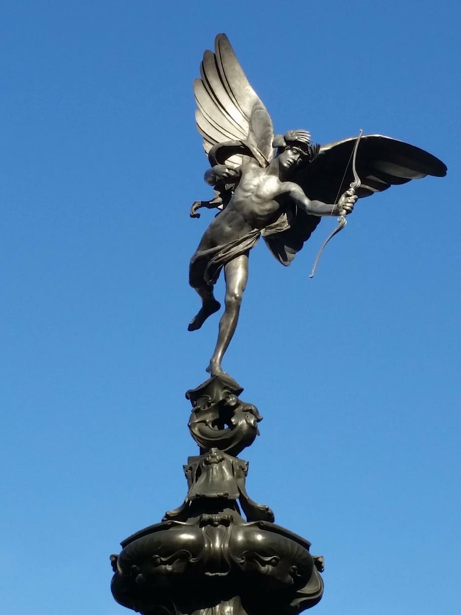 man with wings holding bow statue, eros, love, struck, blue sky