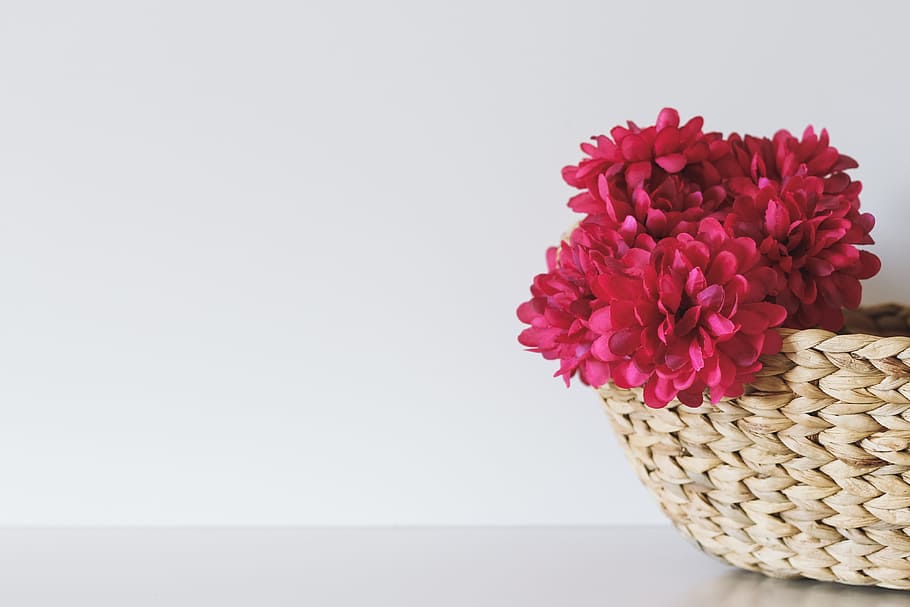 pink petaled flower inside brown wicker basket, red petal flowers on brown woven basket