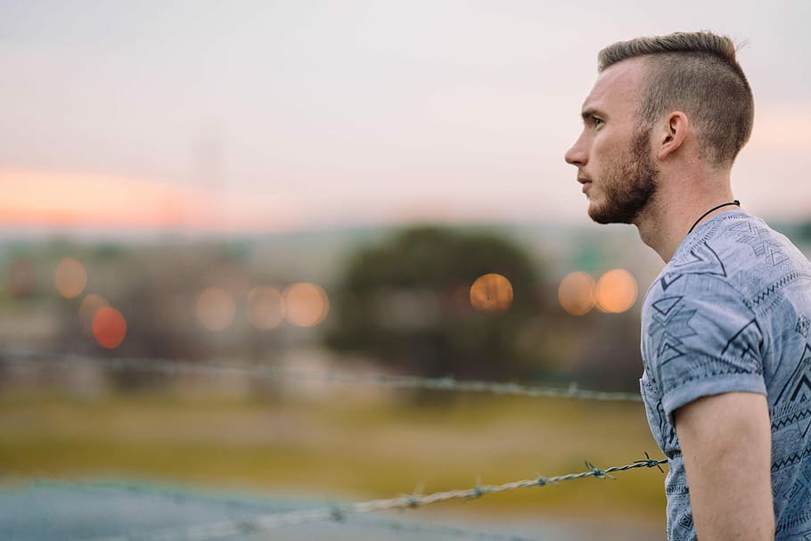 man wearing gray leaning on barbwire, man standing near gray barbwire during daytime HD wallpaper