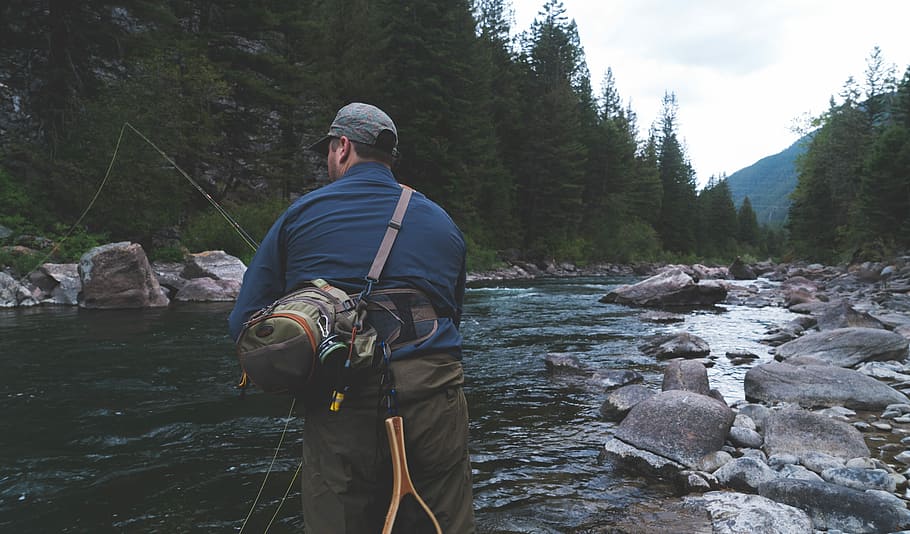 man fishing on river at daytime, man holding fishing rod near trees HD wallpaper