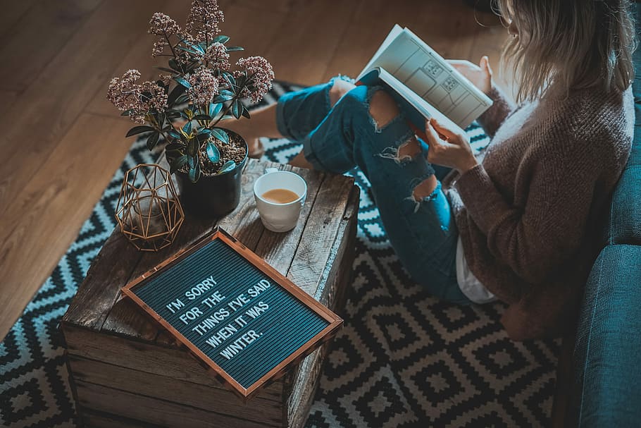 woman sitting on area rug, woman wearing brown cardigan holding book HD wallpaper