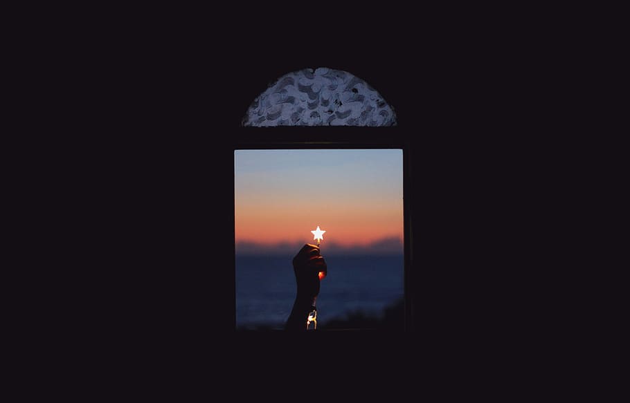 persona holding star near the window during sunset, low-light photography of person's hand holding star light near window through clam body of water during golden hour HD wallpaper