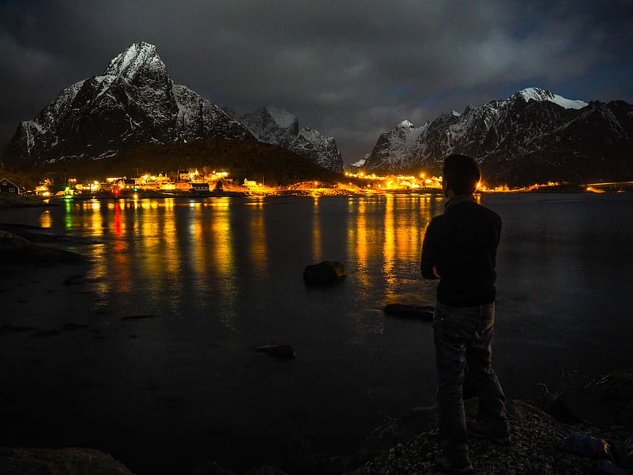 man standing near body of water far away from building during nighttime, The Lofoten Islands HD wallpaper