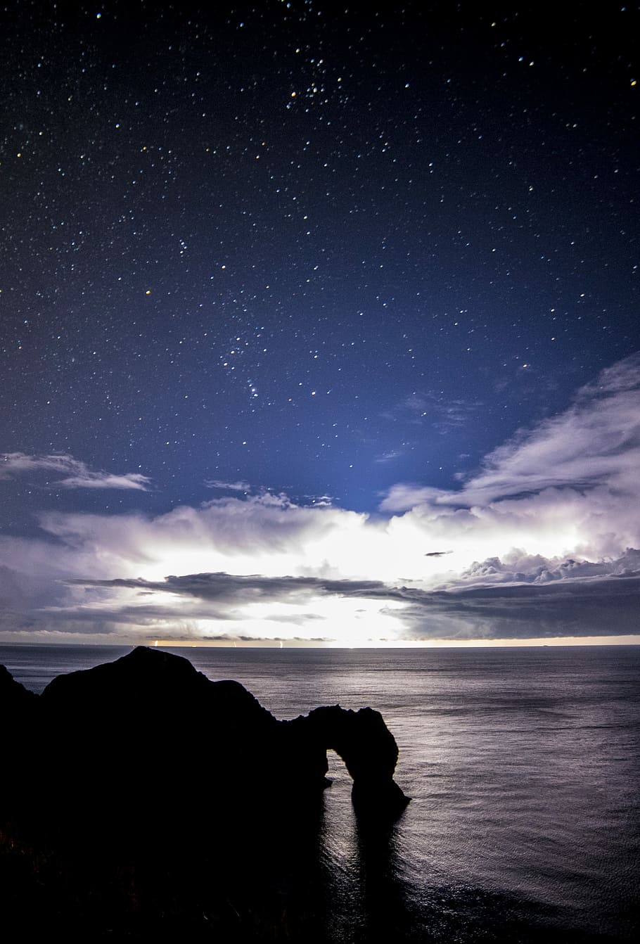 body of water across mountain, silhuoette of rock, sky, stars HD wallpaper