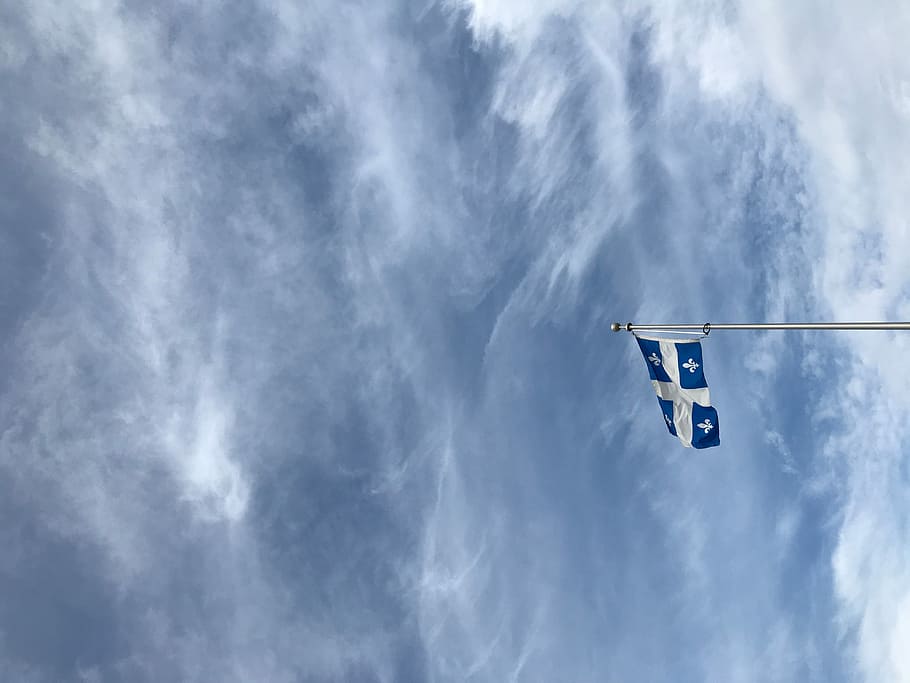 Quebec flag, white and blue with cross flag with sky as background