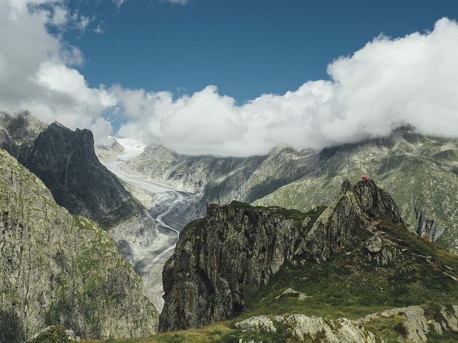 brown and green rock formation under blue and white clouds, photography of mountain covered by clouds HD wallpaper